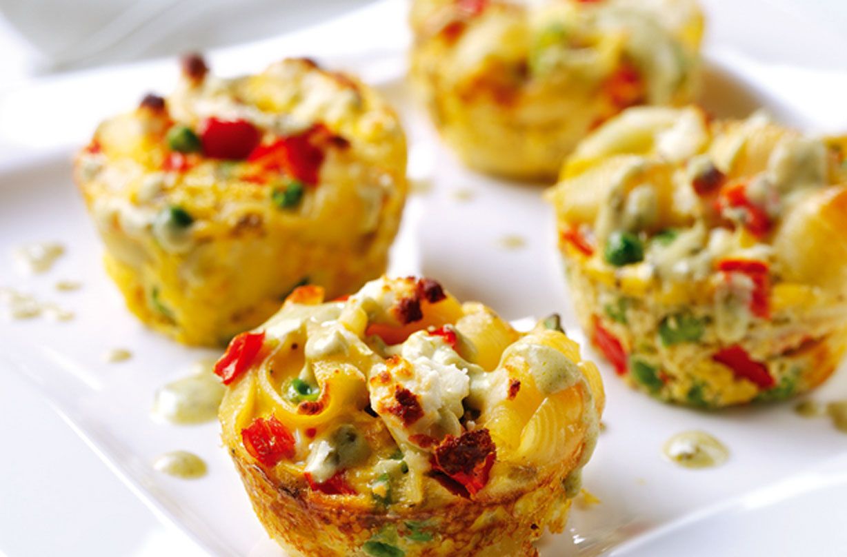 Mini vegetable frittatas with pasta, peppers, and cheese on a white plate
